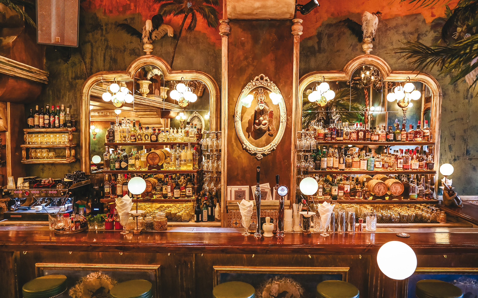 Bar interior in Athens with ornate mirrors and shelves stocked with spirits, part of a night tour experience.