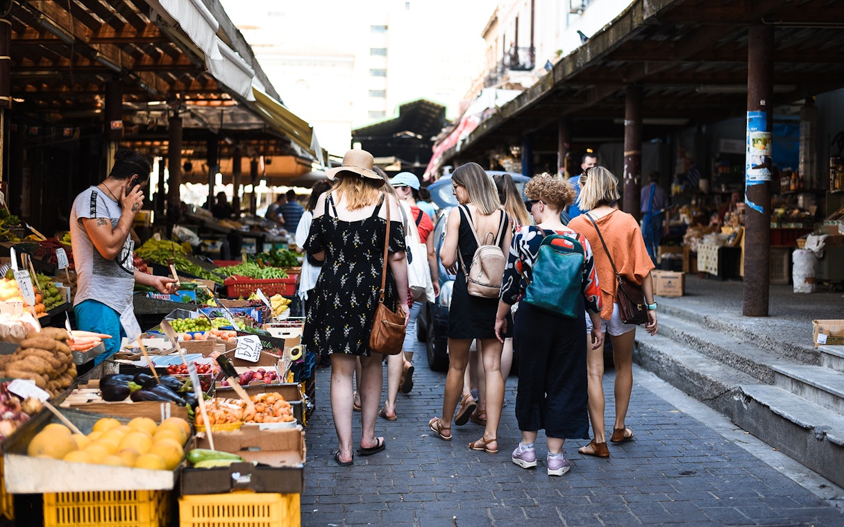 Tourists exploring a vibrant market in Athens during a food tour.