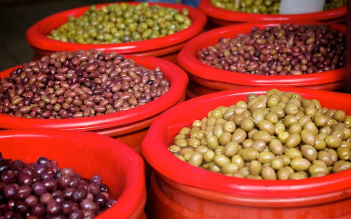 Variety of olives in red bowls at Athens market during food tour.