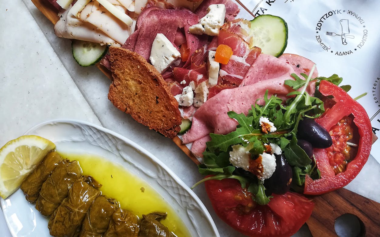 Athenian food tour platter with meats, cheeses, olives, and dolmades in Athens.