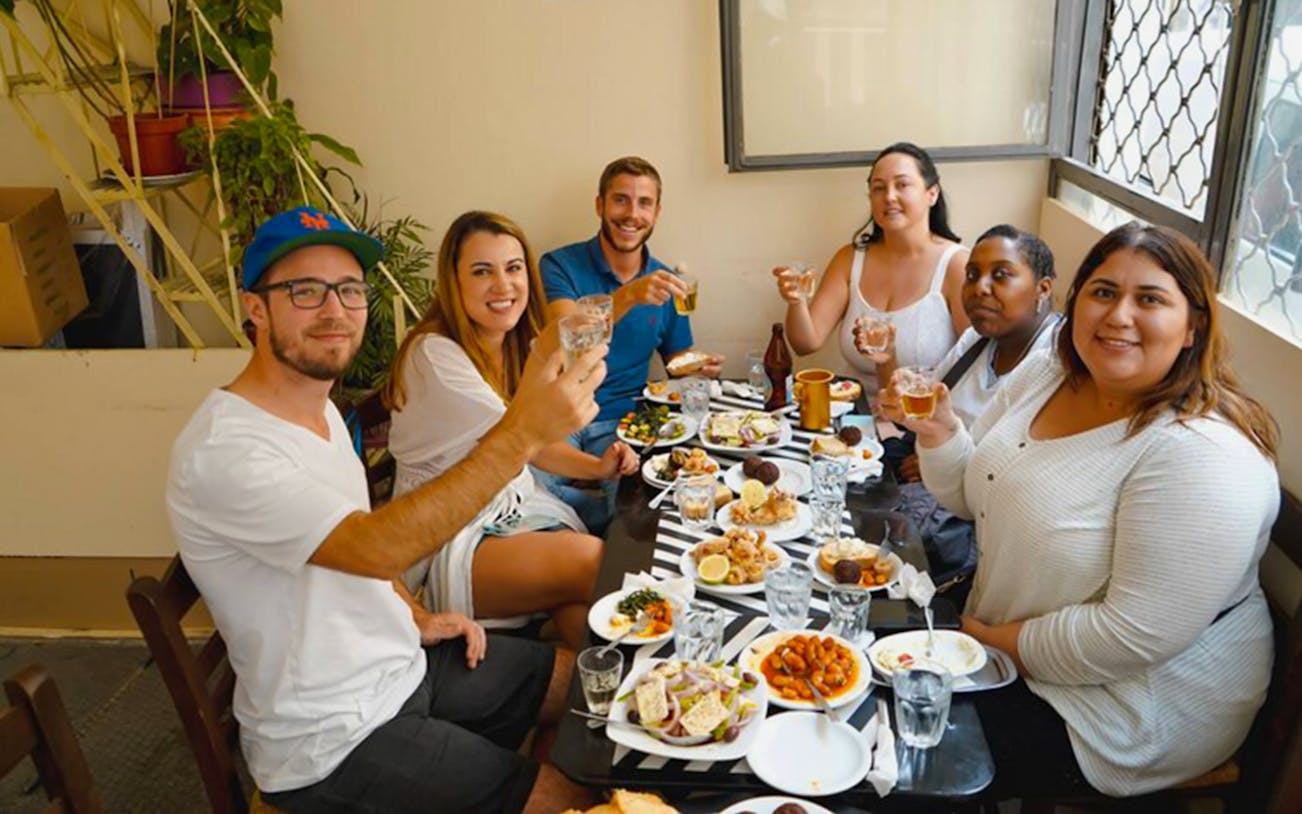 Group enjoying traditional Greek dishes on Athens street food tour.