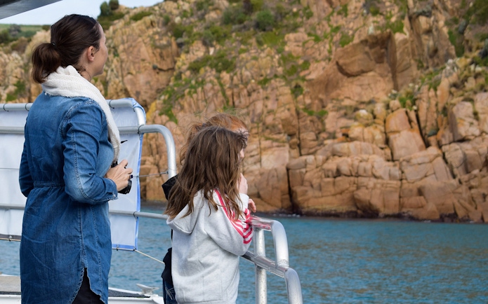 Tourists on a boat admire rocky cliffs during Cape Woolamai morning cruise, Phillip Island.