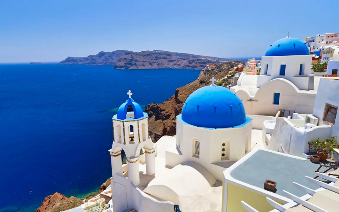 White buildings with blue domes overlooking the sea in Santorini, Greece.