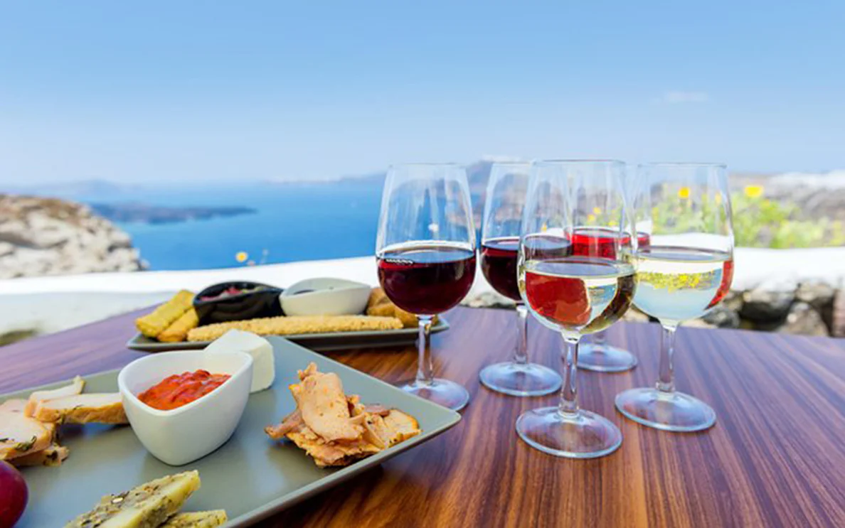 Wine glasses and appetizers on a table overlooking the sea in Santorini.