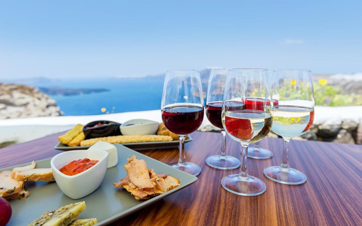 Wine glasses and appetizers on a table overlooking the sea in Santorini.