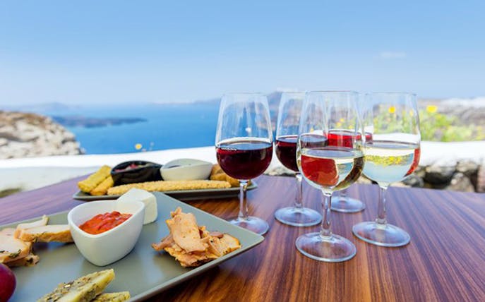 Wine glasses and appetizers on a table overlooking the sea in Santorini.