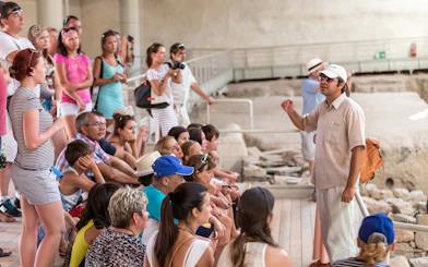 Tour group listening to a guide at an archaeological site in Santorini.