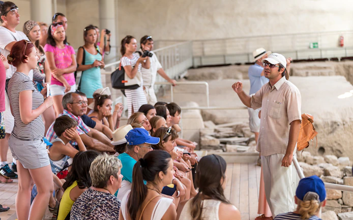 Tour group listening to a guide at an archaeological site in Santorini.