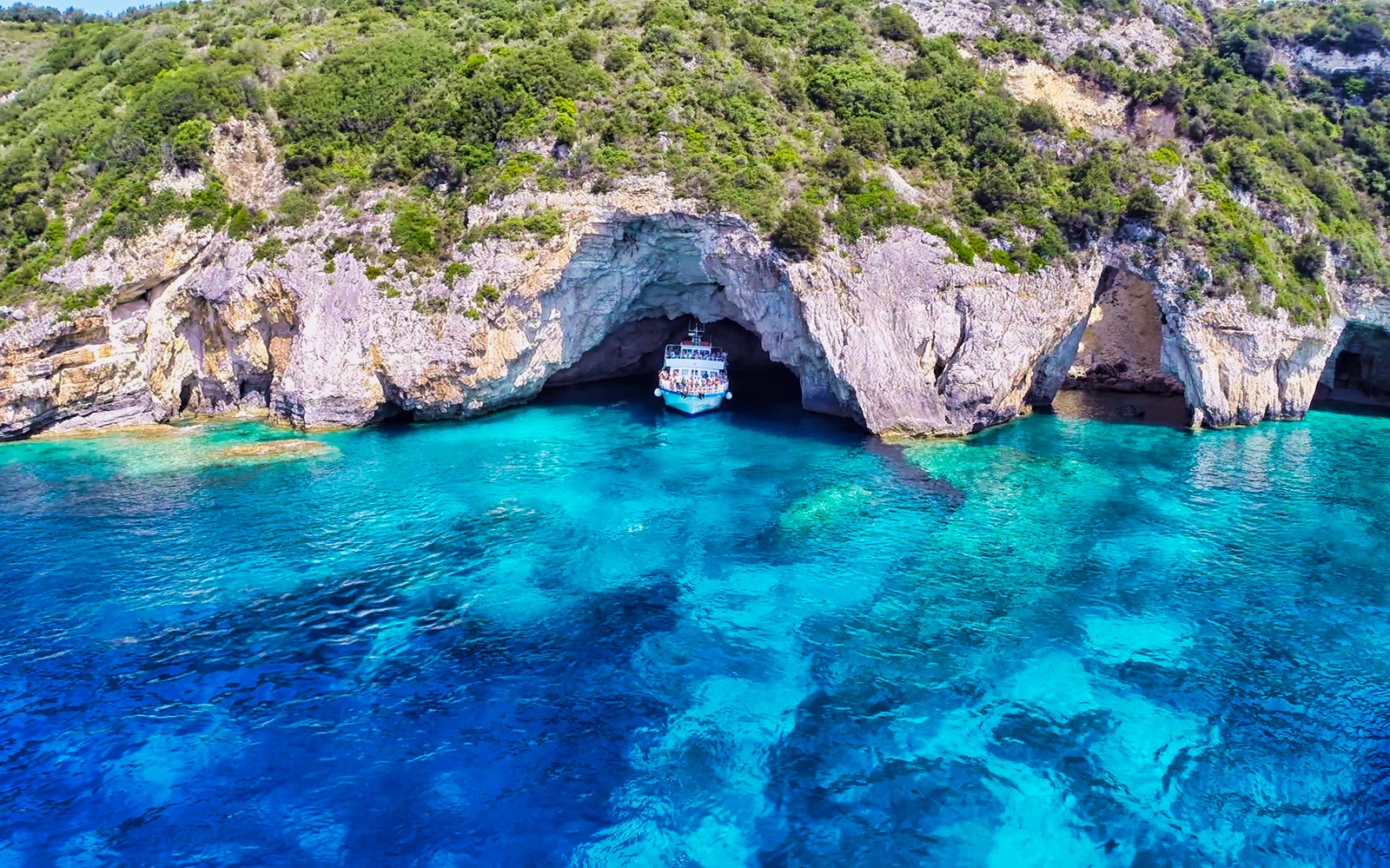 Corfu day cruise boat near Paxos Antipaxos Blue Caves with Gaios village in view.
