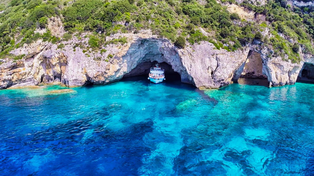 Corfu day cruise boat near Paxos Antipaxos Blue Caves with Gaios village in view.