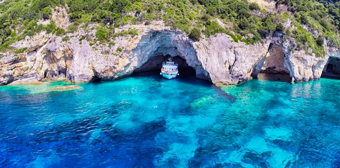 Corfu day cruise boat near Paxos Antipaxos Blue Caves with Gaios village in view.