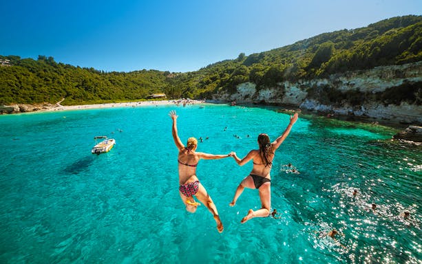 Jumping into clear waters on Paxos Antipaxos day cruise near Lakka village.