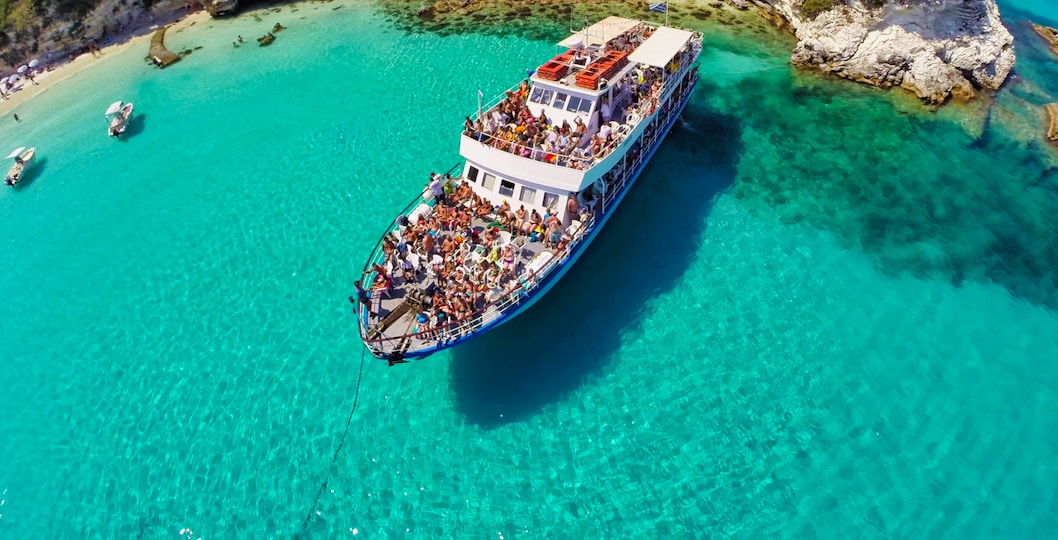 Corfu day cruise boat near Paxos Antipaxos Blue Caves with Lakka village in view.