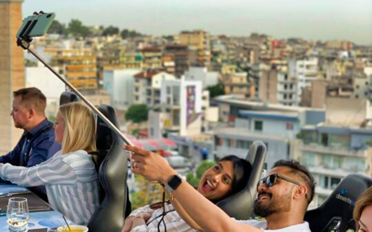 Guests taking a selfie during Dinner in the Sky experience in Athens with cityscape view.