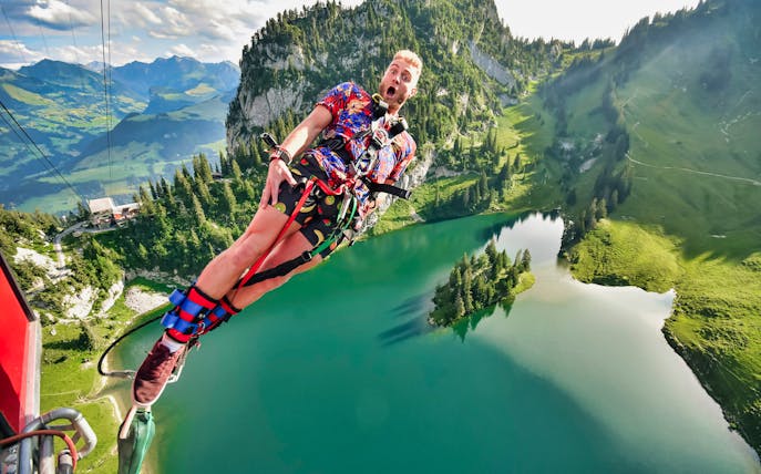 Bungy jumping over Stockhorn Lake with scenic mountain view, Switzerland.