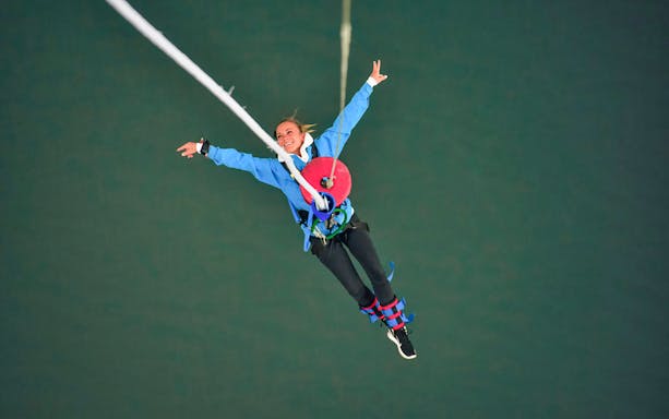 Bungy jumper mid-air at Stockhorn, Switzerland, with arms outstretched.