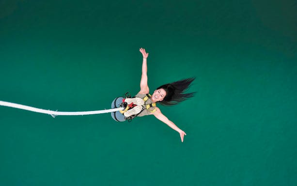 Person bungy jumping over turquoise water at Stockhorn, Switzerland.