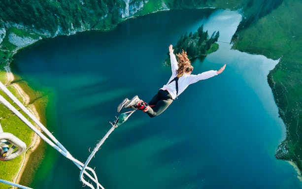 Bungy jumper leaping over Stockhorn lake with scenic view, Switzerland.