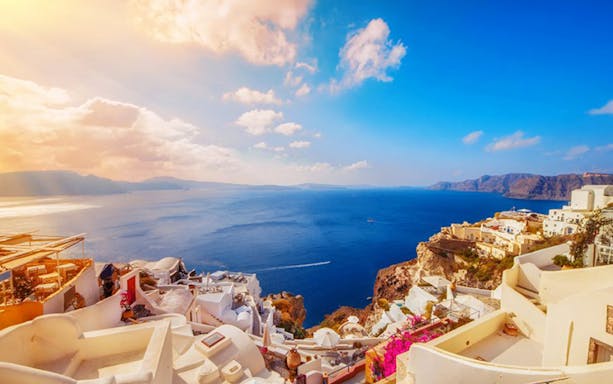 Santorini caldera view with white buildings and blue sea during sunset boat tour.