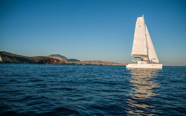 Sailing boat on the Aegean Sea during Santorini sunset tour.