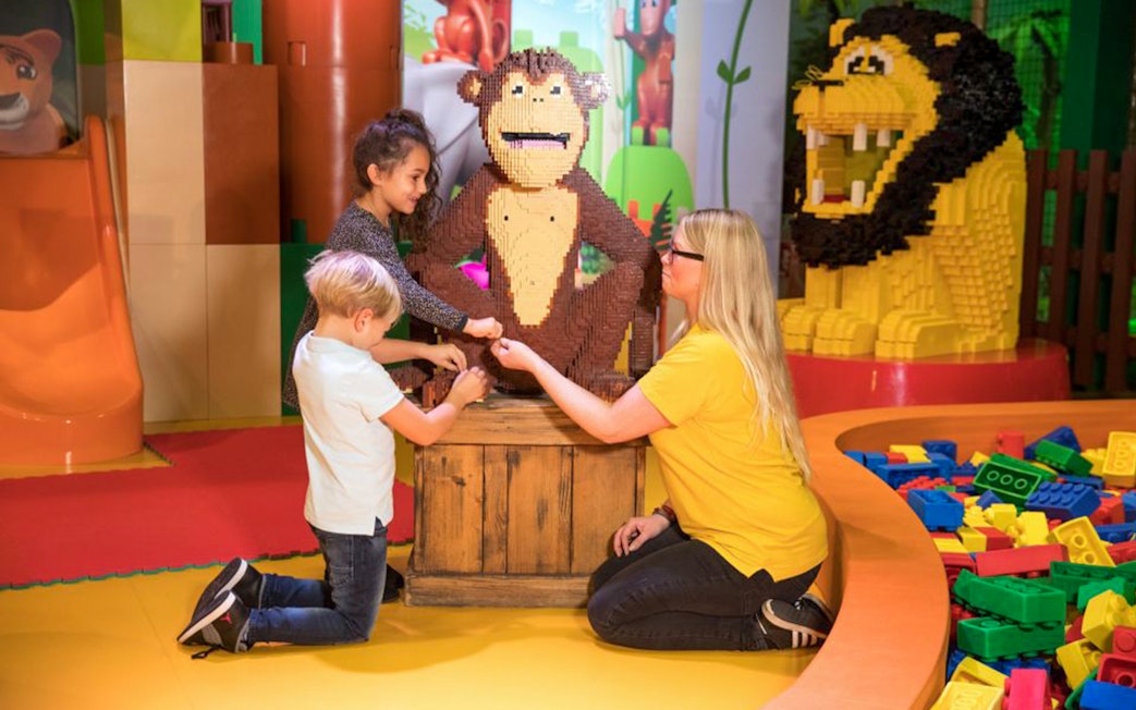 Children and adult interacting with LEGO monkey sculpture at LEGOLAND Discovery Centre Oberhausen.