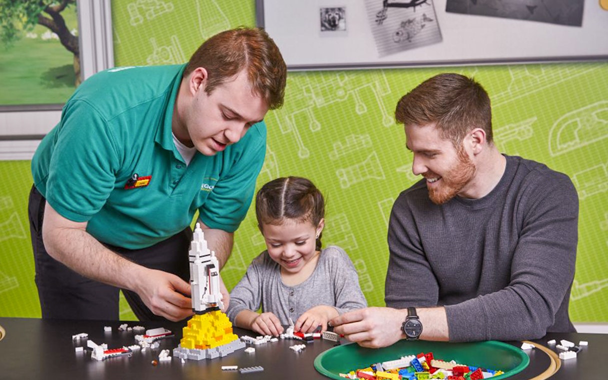 Child building LEGO rocket with adult assistance at LEGOLAND Discovery Centre Oberhausen.