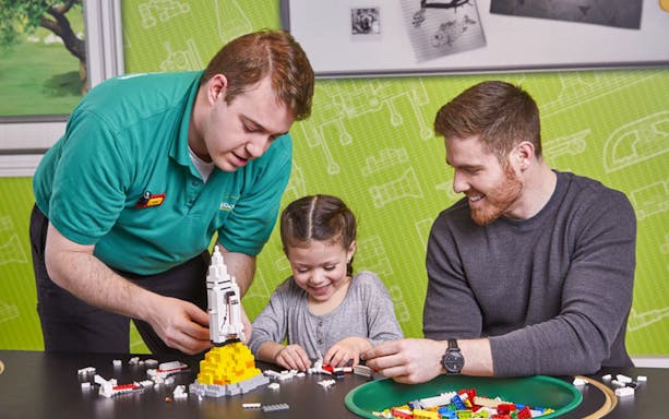 Child building LEGO rocket with adult assistance at LEGOLAND Discovery Centre Oberhausen.