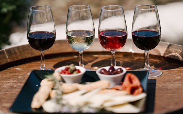 Wine glasses and appetizers on a barrel during Santorini Wine Tour Experience.