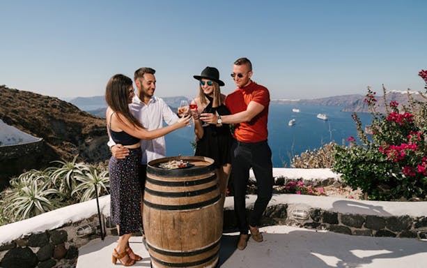 Group enjoying wine tasting on a terrace overlooking the sea in Santorini.