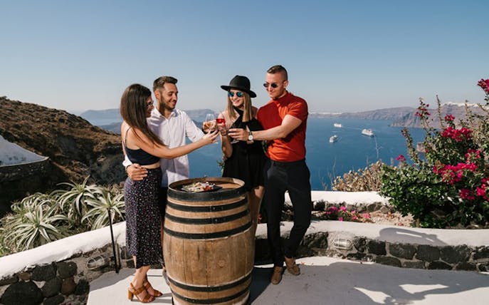 Group enjoying wine tasting on a terrace overlooking the sea in Santorini.