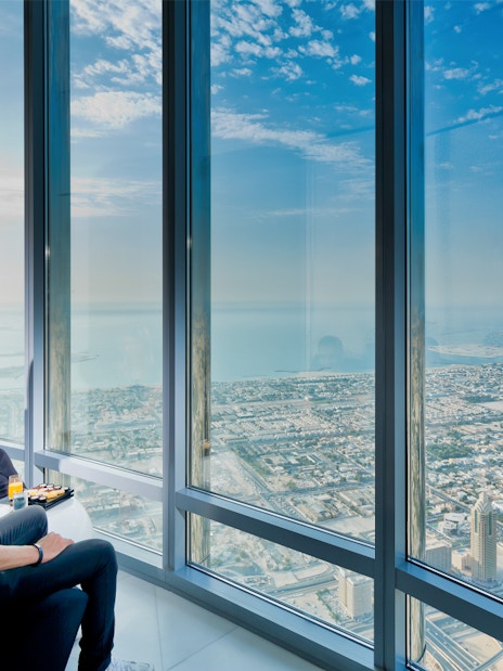 Visitors enjoying city view from Burj Khalifa with coffee and pastries.