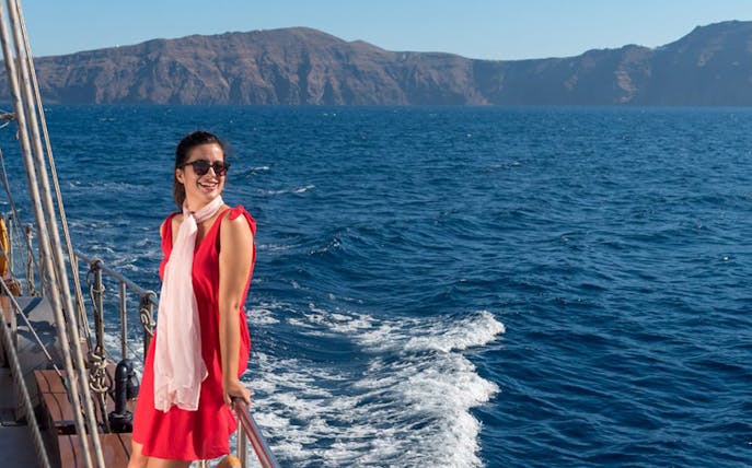 Woman enjoying a boat ride with Santorini caldera view during Full Day Santorini Volcano & Oia Sunset Tour.