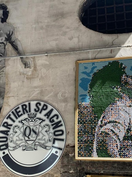 Mural of Diego Maradona in Quartieri Spagnoli, Naples, with mosaic art and local street signs.