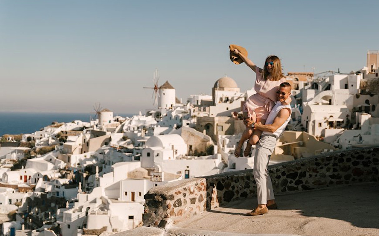 Couple enjoying view of Santorini's white buildings and windmills on a sightseeing tour.