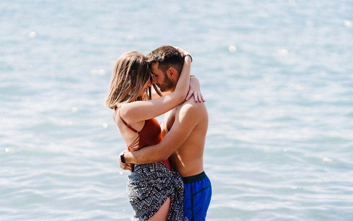 Couple embracing by the sea during Santorini sightseeing tour.