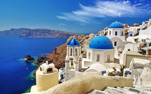 Santorini's blue-domed churches overlooking the Aegean Sea on a sightseeing tour.