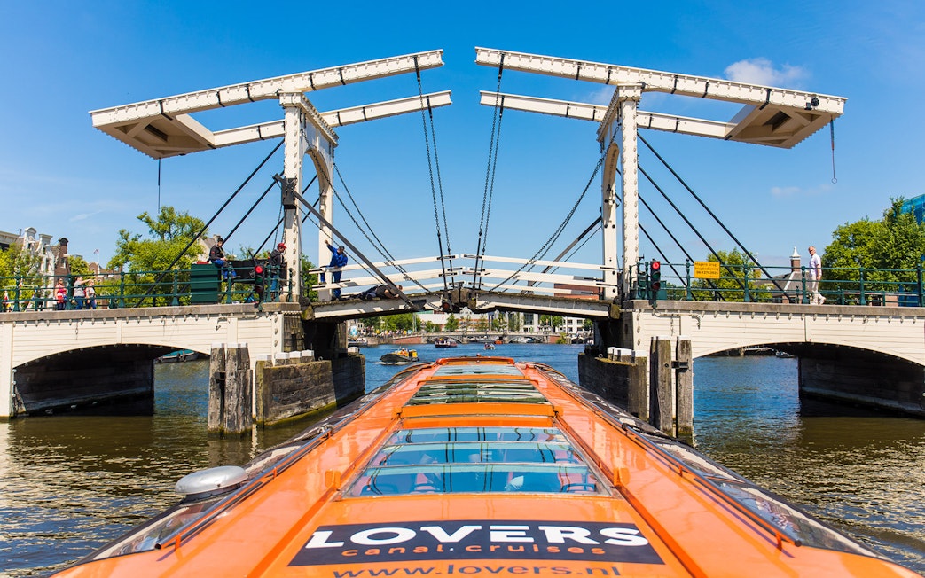 Amsterdam canal cruise boat approaching Magere Brug bridge.