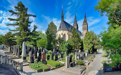 Vyšehrad Castle cemetery with church spires and surrounding greenery in Prague.