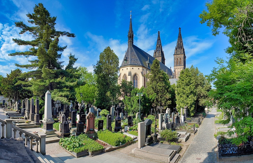 Vyšehrad Castle cemetery with church spires and surrounding greenery in Prague.