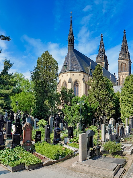 Vyšehrad Castle cemetery with church spires and surrounding greenery in Prague.