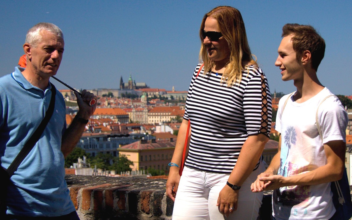 Tourists at Vyšehrad Castle with Prague cityscape in the background.