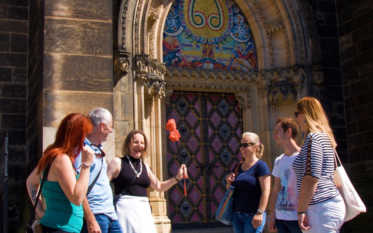 Tour group at Vyšehrad Castle entrance, Prague, with guide holding a flag.