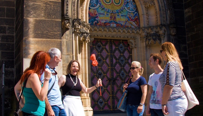 Tour group at Vyšehrad Castle entrance, Prague, with guide holding a flag.