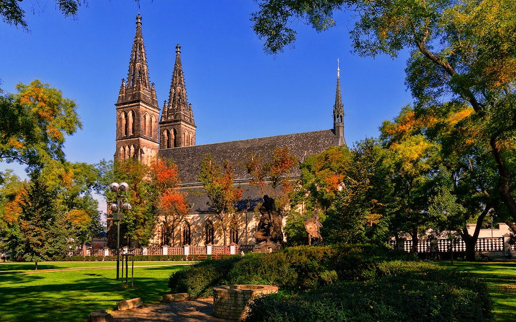 Vyšehrad Castle with twin spires surrounded by trees in Prague, Czech Republic.