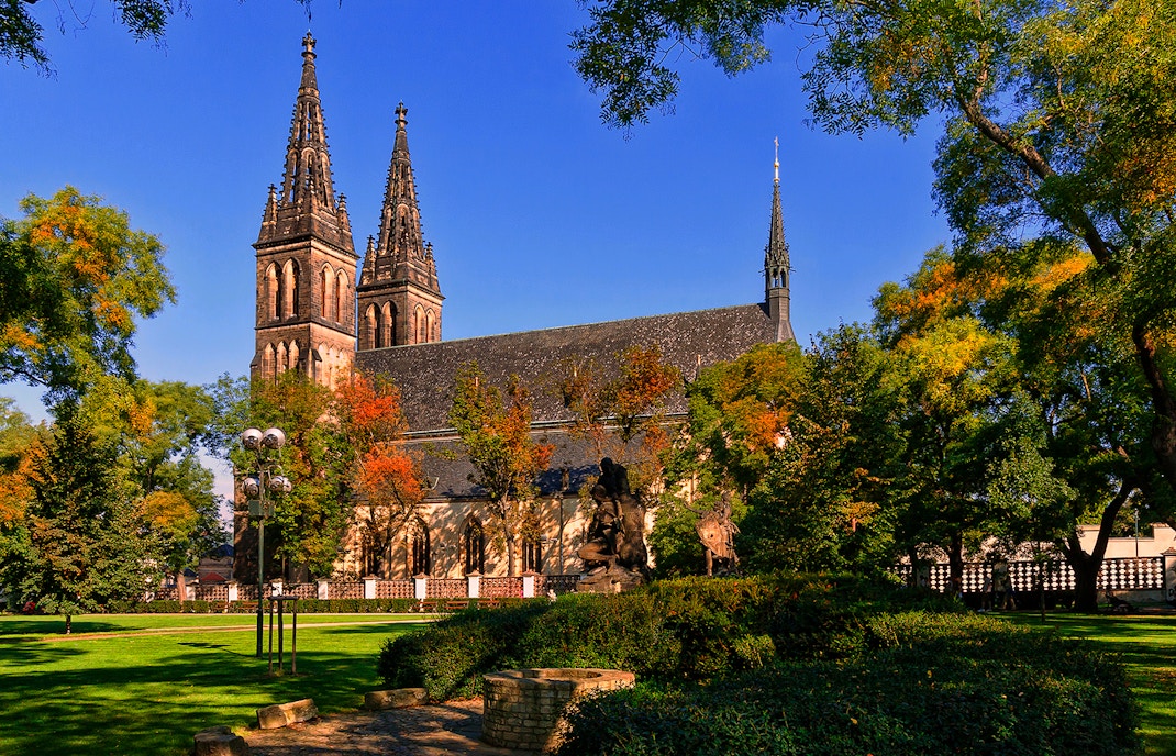 Vyšehrad Castle with twin spires surrounded by trees in Prague, Czech Republic.