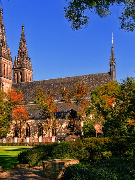 Vyšehrad Castle with twin spires surrounded by trees in Prague, Czech Republic.