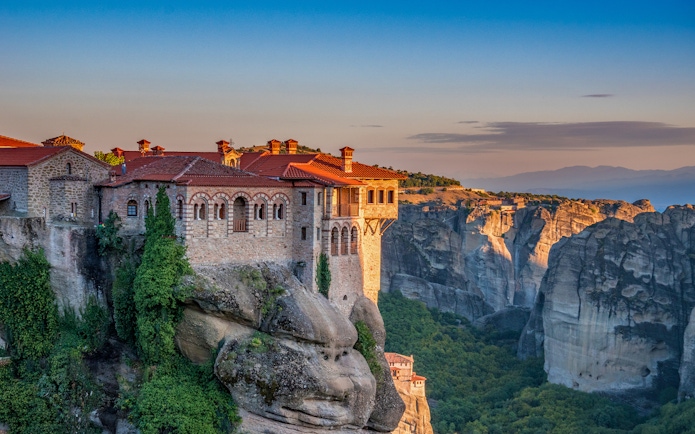Meteora monastery perched on a cliff at sunset during Athens to Meteora full-day trip.