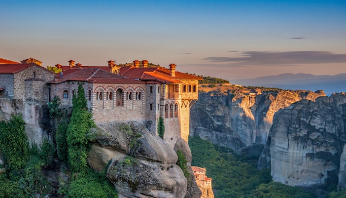 Meteora monastery perched on a cliff at sunset during Athens to Meteora full-day trip.