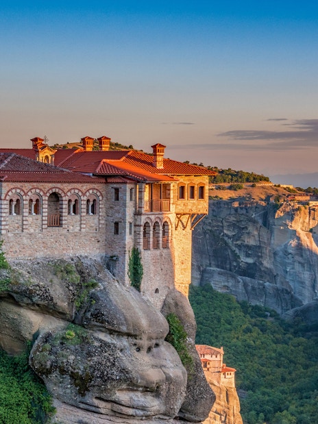 Meteora monastery perched on a cliff at sunset during Athens to Meteora full-day trip.
