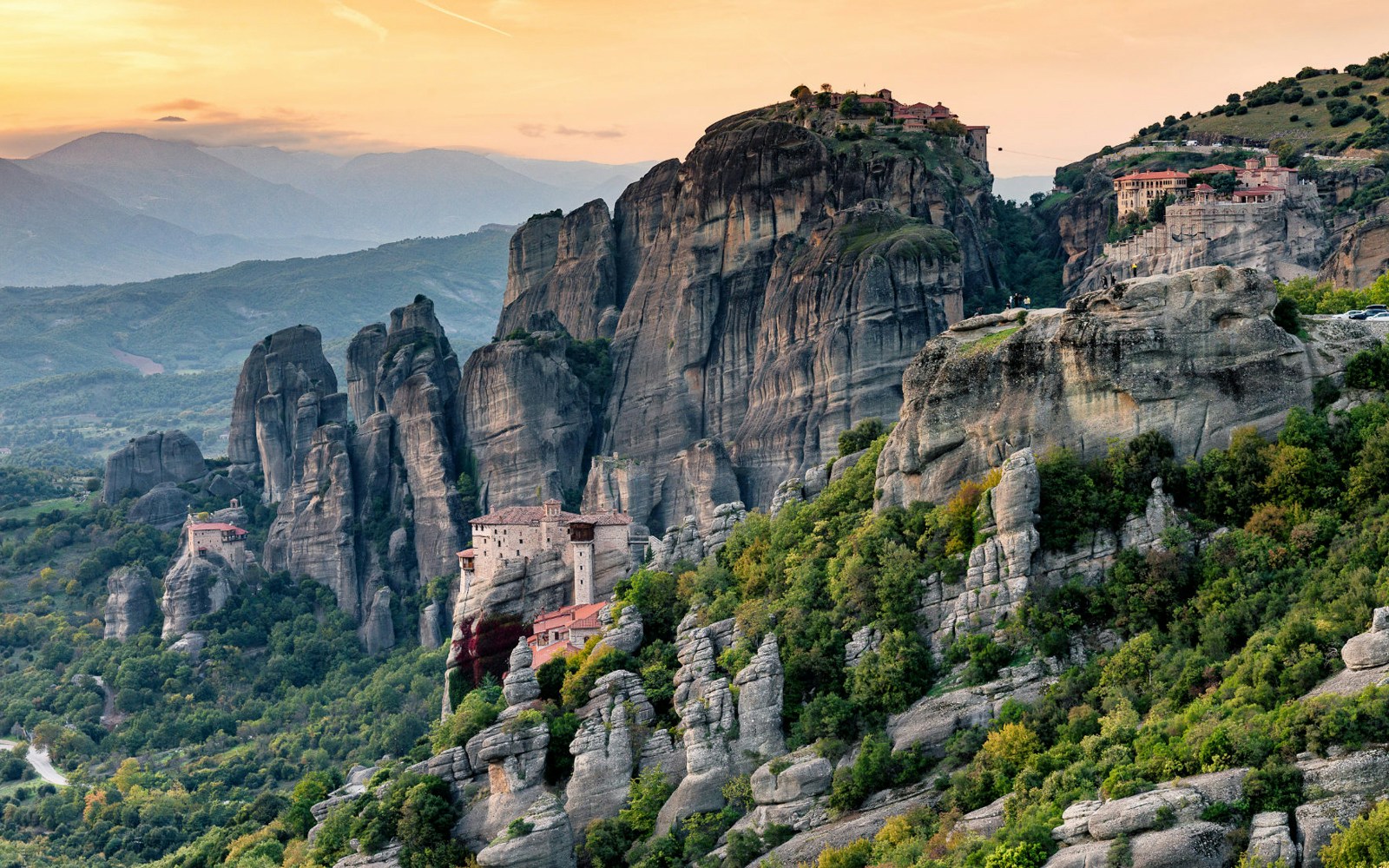 Meteora monasteries perched on rock formations at sunset, Greece.
